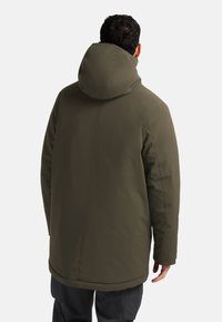 Donkergroene hoodie-jack met een zachte textuur, naaddetails en een middelgrote lengte, geschikt voor casual of buitengebruik.