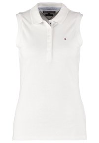 Vit ärmlös polo med strukturerad tyg, som har en knäppt knappslå och en liten broderad logotyp på bröstet.