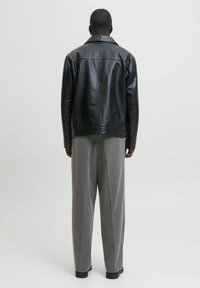 Black leather jacket with a spread collar, straight-cut design, paired with light gray wide-leg trousers. Simple and smooth texture.