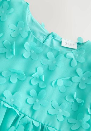 Türkiissinine kleit, millel on tekstuuriga lillest embelish, ümmargune dekoltee ja kogutud seelik. Sildi peal on kirjutatud "NEXT", mis näitab brändi päritolu.