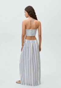 Strapless two-piece outfit featuring a fitted striped crop top in white and blue, paired with a long, flowing skirt with similar stripes.