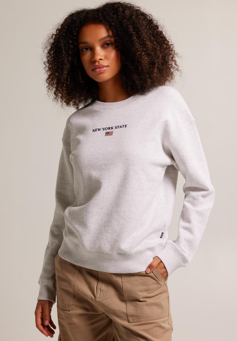 Grey sweatshirt with crew neck, featuring "NEW YORK STATE" in dark letters and an American flag graphic. Relaxed fit, cotton material.