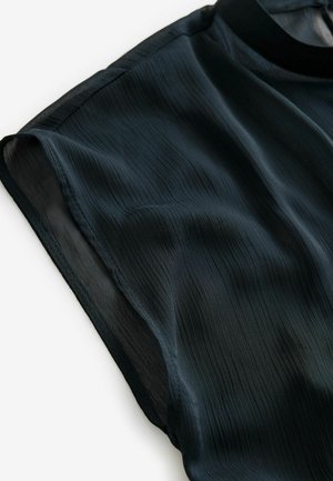 Blusa nera leggera con un tessuto strutturato a righe verticali, colletto alto e maniche corte. Caduta liscia e fluida.