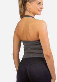 Grijs aansluitend top met halternekdesign, gladde textuur en rekbare stof, gecombineerd met high-waisted zwarte leggings.