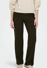 Mörkbruna vida byxor med en slät textur. Har framseams och en enkel design, i kombination med en ljusfärgad överdel.