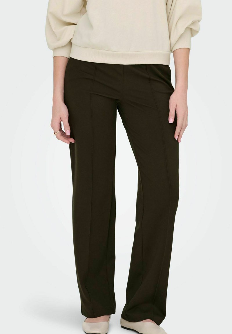 Mörkbruna vida byxor med en slät textur. Har framseams och en enkel design, i kombination med en ljusfärgad överdel.