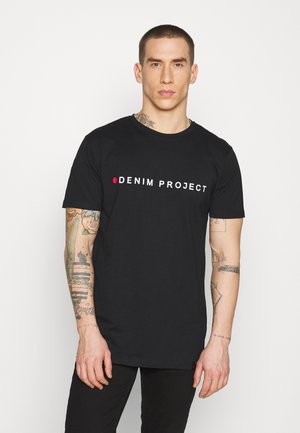 Czarna bawełniana koszulka z krótkim rękawem, z napisem "DENIM PROJECT" w białych i czerwonych literach z przodu. Model pokazuje widoczne tatuaże.