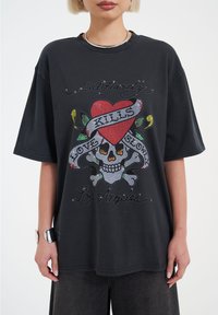 Černé oversized tričko s designem kostky, srdce a stužky zdobené kamínky, s nápisy "Ed Hardy" a "Los Angeles."