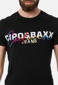Schwarzes Baumwoll-T-Shirt mit dem Schriftzug "Cipo & Baxx Exclusive Jeans" in fettem Weiß und buntem gesticktem Text, mit Rundhalsausschnitt und kurzen Ärmeln.