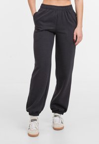 Zwarte katoenen joggingsbroek met een elastische tailleband en zijzakken, met een taps toelopend ontwerp bij de enkels.