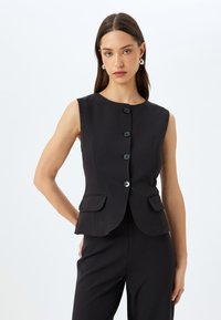 Zwarte mouwloze vest met vijf knopen, kleine voorkruiken, aansluitend ontwerp, subtiele glans en een ronde halslijn.