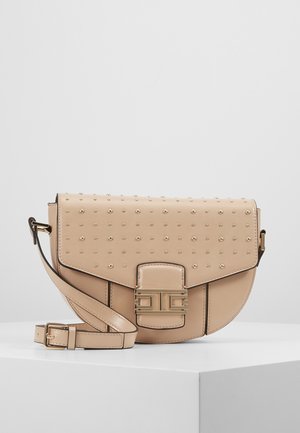 Beżowa skórzana torebka na ramię z złotymi ćwiekami, regulowanym paskiem oraz złotym geometrycznym zapięciem na zakrzywionej klapie, prezentowana na białym tle.
