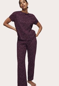 Lilla mønstret pyjamassæt med kortærmet top og løstsiddende bukser med et diskret plettet design. Blødt stof, afslappet pasform.