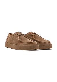 Zapatos de ante marrón con punta redondeada, diseño con cordones y suela de goma texturizada. Presenta costuras en color beige a lo largo del borde para un toque de detalle.