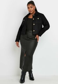 Svart kort jacka med guldknappar, två framfickor; matchad med en höga sprund, mörkgrön läderkjol; svarta kängor.