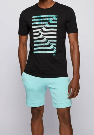 Schwarzes T-Shirt mit wiederholtem "BOSS"-Text in Türkis und Weiß, kombiniert mit hellen Türkis-Shorts mit logo-prägten Saumkanten.