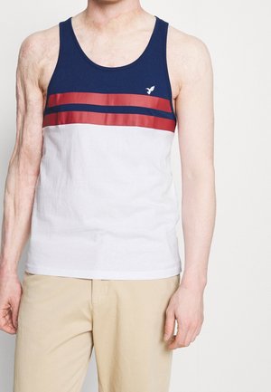 Navy and white sleeveless tank top featuring red horizontal stripes, made of cotton with a soft texture, and a small logo on the chest.
