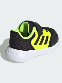 Black athletic shoe with a mesh upper, featuring a bright yellow accent and three black stripes. Includes a Velcro strap and white sole.