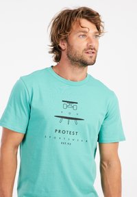 Tyrkysové bavlněné tričko s grafikou skateboardu a surfboardu. Text: "POV PROTEST SPORTSWEAR EST.93." Krátké rukávy.