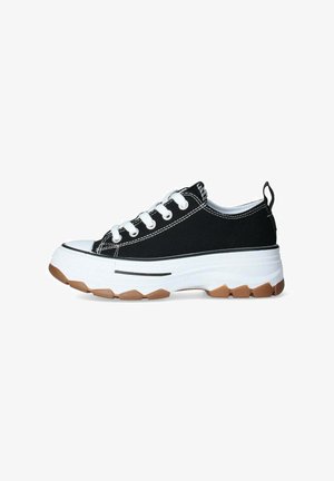 Zapatillas de lona negras con una entresuela gruesa blanca y suela de goma texturizada, con cordones blancos y detalles de costura en contraste.