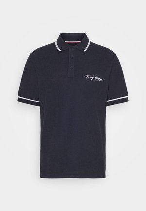 Granatowy polo z białym wykończeniem na kołnierzyku i rękawach, zapięcie na trzy guziki oraz logo "Tommy Hilfiger" na lewej piersi.