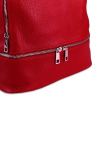 Sac à main en cuir rouge avec une finition texturée, doté de fermetures éclair argentées et de tirettes à double fermeture éclair en bas pour un accès facile.