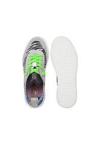 Sneaker con stampa zebra grigia e nera, con lacci verde fluorescente, suola bianca texturizzata e accento sul tallone multicolore. Presenta una soletta ammortizzata.