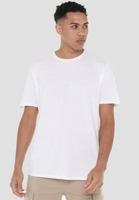 White cotton t-shirt with a crew neck, short sleeves, and a relaxed fit. Smooth texture, minimalistic design, no visible patterns or logos.