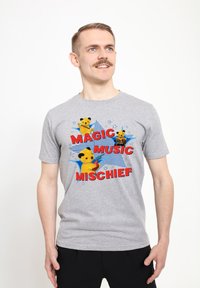 Šedé bavlněné tričko s barevným grafickým potiskem zobrazujícím žluté medvědí postavy, text "MAGIC MUSIC MISCHIEF" a modré hvězdné akcenty.
