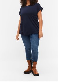 Marinblå t-shirt med kort ärm, lös passform. Mixad med blå jeans i medelhög midja och bruna ankelstövlar med svarta detaljer och tjocka sulor.