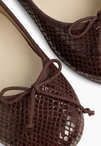 Ballerines en cuir marron avec un motif en maille texturée et brillant, dotées d'un accent en forme de nœud et d'une doublure intérieure lisse.