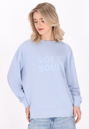 Lichtblauwe sweatshirt met een ronde hals, verlaagde schouders en een tekstprint aan de voorkant met de tekst "Ik heb een ZACHTE ZIEL."