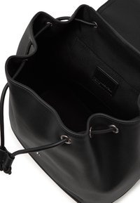 Black leather bucket bag with a textured exterior, drawstring closure, and silver-tone eyelets. Interior features a smooth fabric lining.