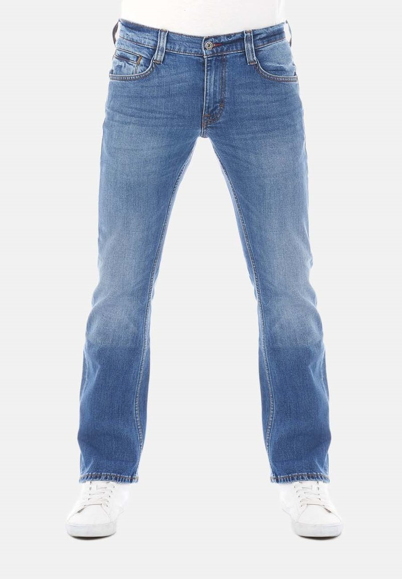 Jeans de mezclilla azul claro con corte recto, que cuentan con cinco bolsillos, cierre frontal con botón y un desgaste sutil en las piernas. Combinados con zapatillas blancas.