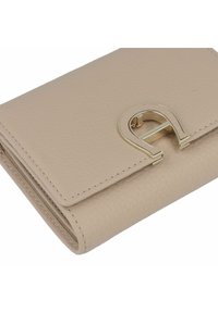 Portafoglio in pelle beige con finitura testurizzata, dotato di una chiusura metallica dorata a forma della lettera stilizzata 'A'.