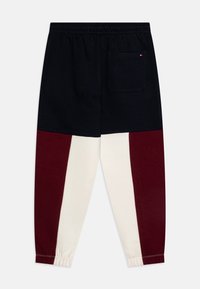 Bomulls joggingbyxor med en svart överdel, med vinröda och cremefärgade vertikala paneler på benen, resår i midjan och bakficka.