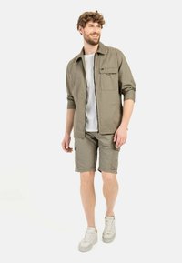 Lichtkhaki shirt en shorts, beide gemaakt van lichtgewicht materiaal. Het shirt heeft een knoopzak op de borst; de shorts hebben zijcargo zakken.