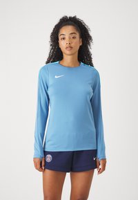 Világoskék, hosszú ujjú sportfelső kerek nyakkal és Nike logóval. Párban sötétkék rövidnadrággal, amelyen Párizs logója található. Sima anyag, testhezálló dizájn.