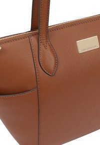 Bruine leren tote bag met een gladde textuur, ritssluiting en hardware in goudkleur. Bevat een zijvak en een gegraveerde logo plaat.