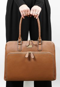 Bruine leren handtas met twee bovenhandvatten, dubbele ritscompartimenten, decoratieve stiksels en subtiele metalen accenten. Soepele textuur, gestructureerd ontwerp.