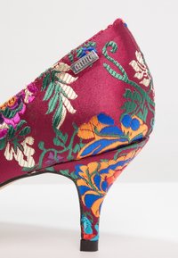 Scarpa con tacco alto ricamata, con una base in raso borgogna, caratterizzata da motivi floreali in verde, arancione e viola, e un tacco nero.