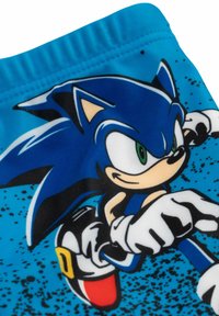 Tessuto blu con Sonic the Hedgehog in una posa di corsa dinamica, indossante guanti bianchi e scarpe rosse con fibbie gialle.