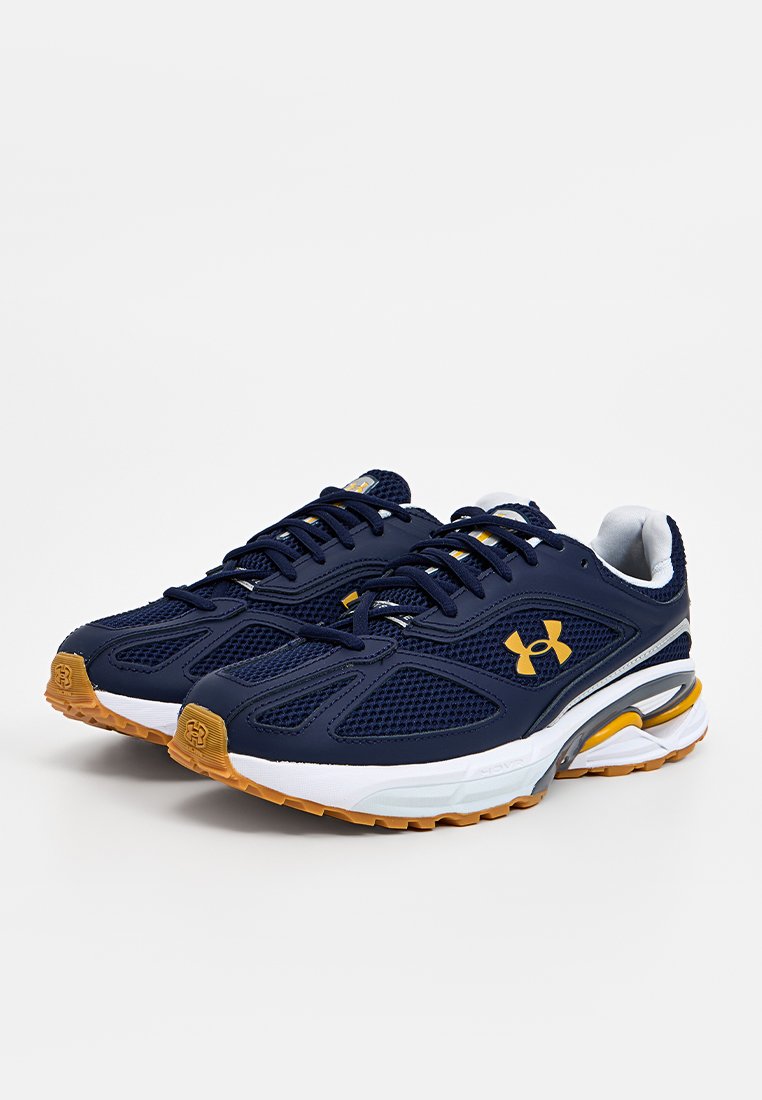 Baskets de sport bleues avec une tige en maille, dotées d'accents jaunes et d'une semelle intermédiaire blanche. Semelle en caoutchouc texturée avec un motif de traction.