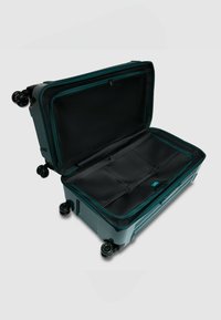 Turquoise harde koffer met dubbele ritssluiting, opengeklapt om een zwarte binnenkant met meerdere vakken en vier wielen voor mobiliteit te tonen.