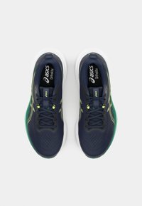 Heren hardloopschoenen met een marineblauwe mesh bovenkant, contrasterende groene accenten en een witte zool met een zwart logo en veters.