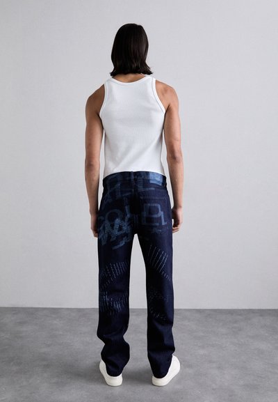 Blugi de un albastru închis cu modele abstracte albastre, asortați cu un top alb fără mâneci. Pantalonii au un design cu picior drept și un talie standard.