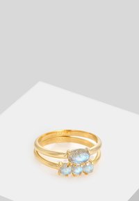 Set aus goldfarbenen Ringen mit drei Bändern und blauen Edelsteinen. Zwei schlanke Bänder halten einen größeren und drei kleinere Steine, die ein elegantes Design präsentieren.