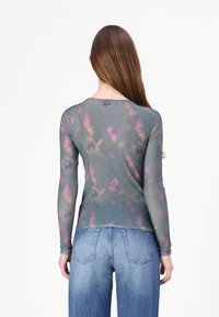Long-sleeve top in sheer, lightweight fabric featuring a muted green base with purple floral patterns. Smooth texture with a round neckline.