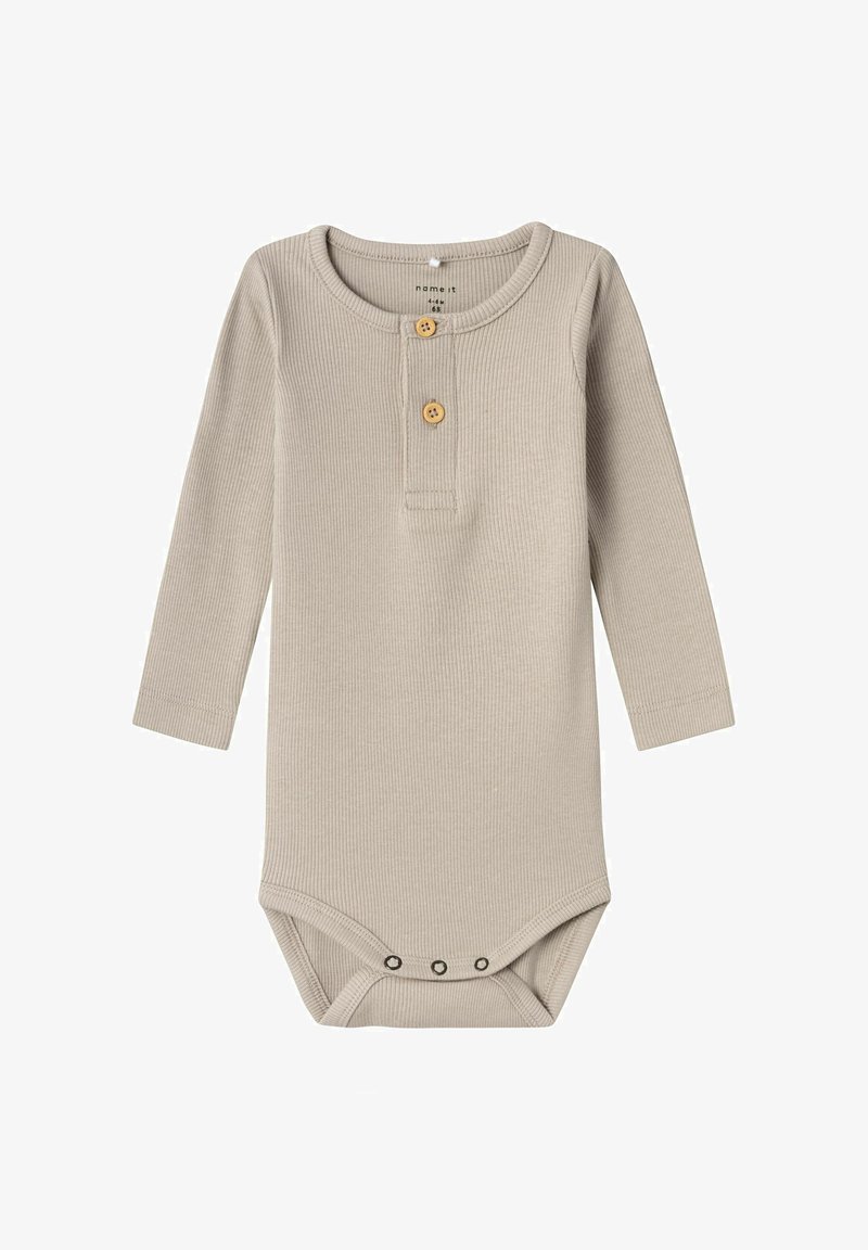 Gaiša bež krāsas garām piedurknēm bodijs ar ribota raksta tekstūru, kam ir divas koka pogas apkaklītē un trīs spiedpogām apakšā.