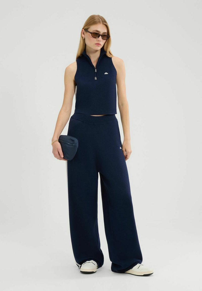 Conjunto de dos piezas en color navy que incluye un top corto sin mangas con cremallera y pantalones de pierna ancha. Tejido suave con un diseño simple y mínima marcación.